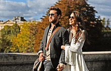 a man and a woman are holding hands while walking across a bridge