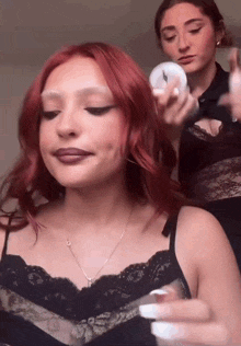 a woman with red hair is getting her hair done by another woman