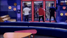 a man in a red vest is standing in front of a red door that says milele