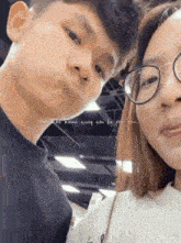 a man and a woman wearing glasses are posing for a picture together .