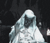 a statue of a man in a white robe is sitting in a dark room