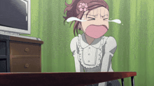 a girl with a flower in her hair is sitting at a table crying
