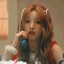 a girl with red hair is holding a fork to her mouth .
