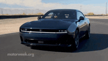 a black car is driving down a road with motorweek.org written in the corner