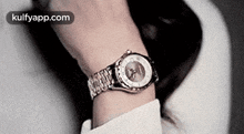 a woman is wearing a watch on her wrist and looking at it