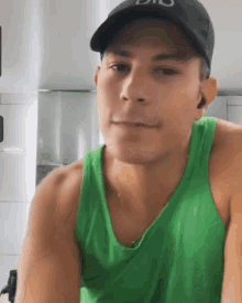 a man is wearing a green tank top and a black hat .