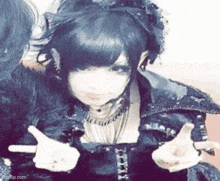the girl is wearing a cat ear wig and giving a thumbs up .