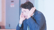 a man covering his ears with his hands while looking down