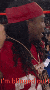 a man wearing a red hat and a necklace with the words i 'm blinged out
