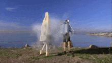 a man and a woman are standing on a cliff near the ocean