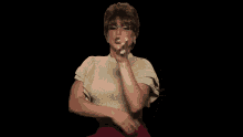 a woman wearing glasses and a gold top is making a gesture