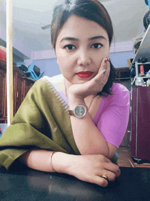 a woman wearing a watch has her hand on her chin and a ring on her left hand