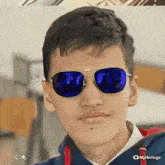 a young man wearing blue sunglasses and a red hoodie