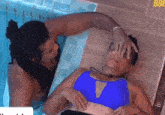 a woman in a blue bikini is laying on a man 's lap in a swimming pool