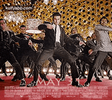 a man in a suit is dancing on a red carpet with a group of men in suits .