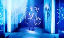 a man is standing in a hallway with blue lights behind him and a drawing on the wall .
