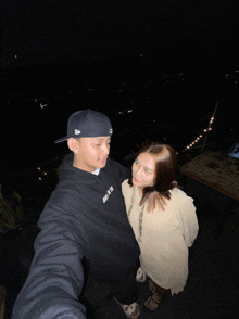 a man wearing a black hoodie that says nike on it poses for a photo with a woman
