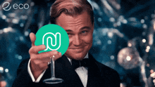 a man in a tuxedo holds a wine glass in front of a green circle with a letter n on it