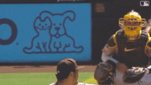 a baseball player throws a ball in front of a sign with a dog and cat drawing on it