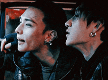 two men with earrings on their ears are looking at something