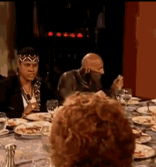a group of people are sitting at a table with plates of food and glasses