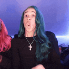 a woman with green hair and a cross necklace makes a funny face