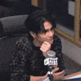 a man is sitting in front of a microphone in a radio station looking at his phone .