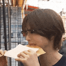 a woman wearing glasses is eating a sandwich