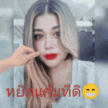 a woman with long blonde hair and red lipstick is being touched by a hand