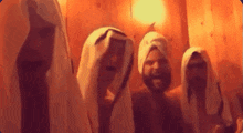 a group of men are standing in a room with towels on their heads