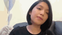 a woman with short hair is sitting on a couch making a funny face .