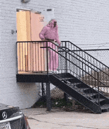 a man in a pink robe is walking up the stairs outside a building