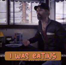 a man is sitting at a table with a sign that says " i was eating "