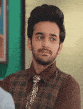 a man with a beard is wearing a brown shirt and tie .