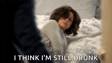 a woman is laying on a bed and saying `` i think i 'm still drunk ''