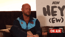 a man sits in front of a sign that says hey crew