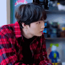 a close up of a person wearing a plaid shirt and earring .