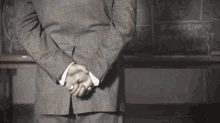 a man in a suit stands in front of a blackboard with math equations written on it