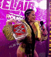 a woman in a leopard print outfit is holding a wrestling belt and a microphone