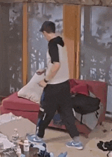 a man is holding a pillow in a messy room .