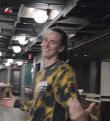 a man wearing a yellow and black tie dye shirt with a tommy hilfiger logo on it