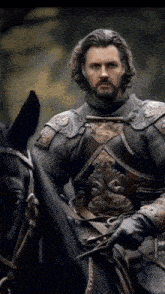 a man in armor is riding a horse with a sword in his hand