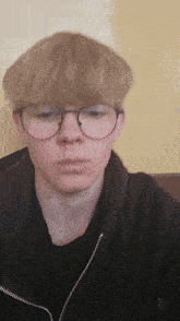a young boy wearing glasses and a black jacket