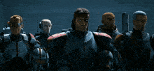 a group of men in armor are standing next to each other in a dark room .