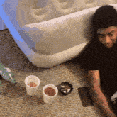 a man is sitting on the floor next to a mattress