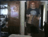 a blurry picture of a man in a room with a poster on the wall that says ' a ' on it
