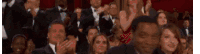 a crowd of people are sitting in a theatre applauding .