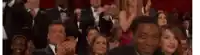 a crowd of people are sitting in a theatre applauding .