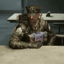 a man in a leather jacket is sitting at a table with a purple box in his hand