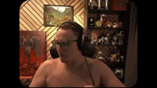 a shirtless man wearing headphones and glasses is standing in front of a shelf filled with toys .